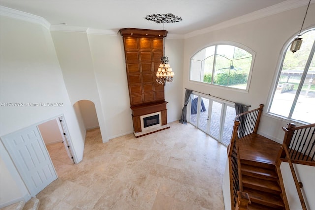 foyer entrance featuring an inviting chandelier, ornamental molding, a large fireplace, and baseboards