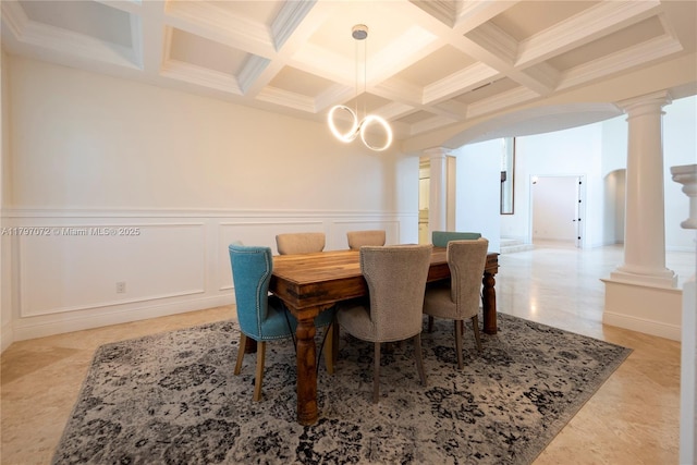 dining area with ornate columns, coffered ceiling, beam ceiling, a wainscoted wall, and a decorative wall