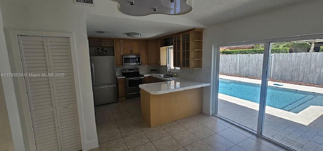 14661 SW 50th St, Miami, FL 33175 - kitchen featuring a sink, a peninsula, light countertops, light tile patterned floors, and appliances with stainless steel finishes