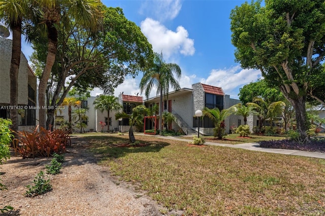 view of front of property featuring a front yard, stucco siding, and a tiled roof