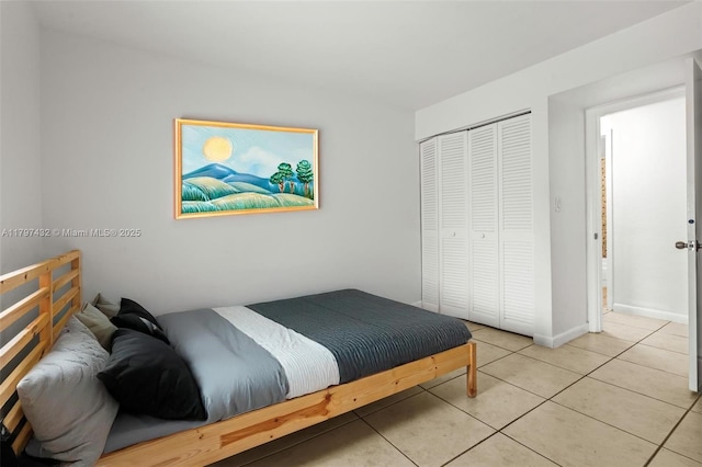 bedroom featuring light tile patterned floors, baseboards, and a closet