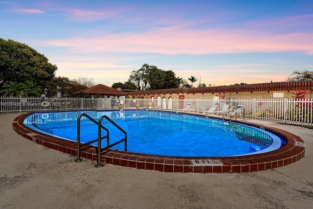 pool at dusk with fence and a community pool