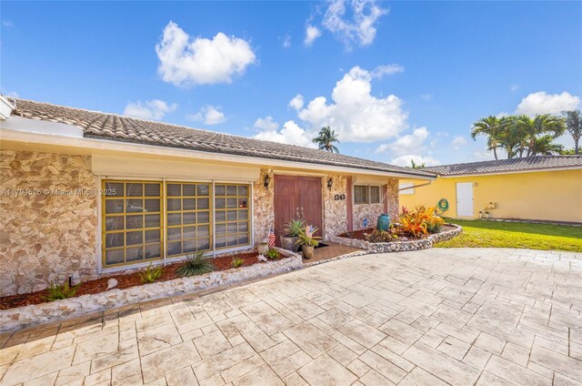1243 Funston St, Hollywood, FL 33019 - view of front of property featuring stone siding and a patio