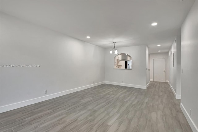 unfurnished dining area with baseboards, a chandelier, recessed lighting, and wood finished floors