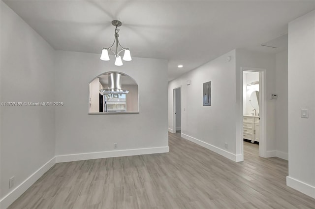 unfurnished room with recessed lighting, a chandelier, light wood-style flooring, arched walkways, and baseboards