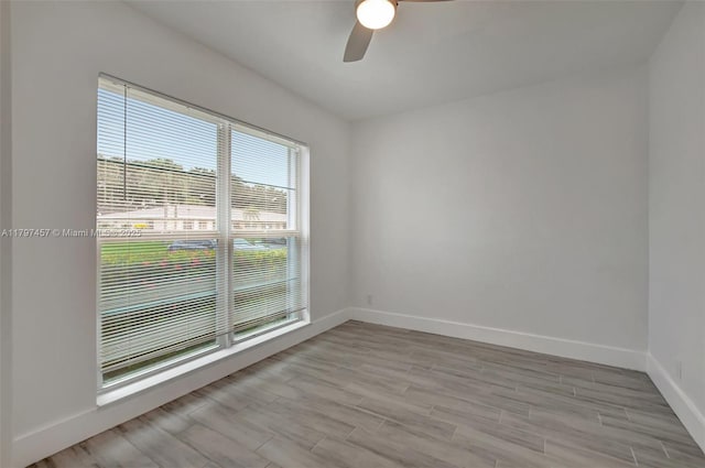 spare room featuring a ceiling fan, baseboards, and wood finished floors