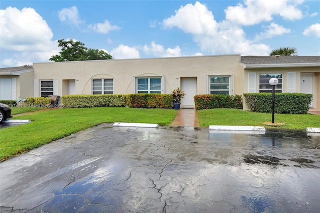 view of front of home with uncovered parking, stucco siding, and a front lawn