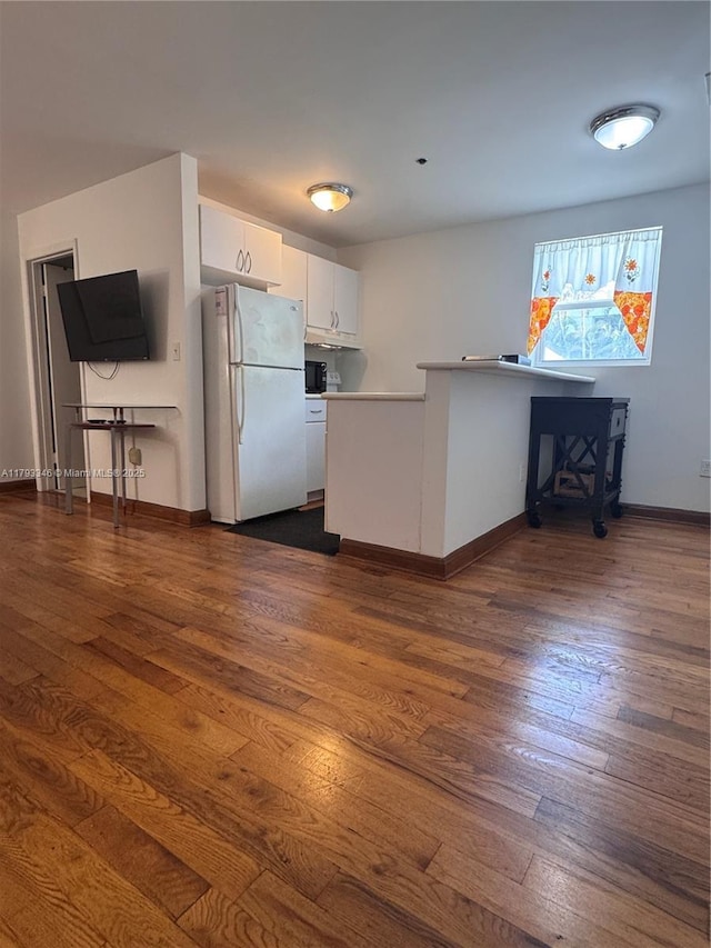 361 Collins Ave Unit A2, Miami Beach, FL 33139 - kitchen with freestanding refrigerator, baseboards, dark wood finished floors, and white cabinetry