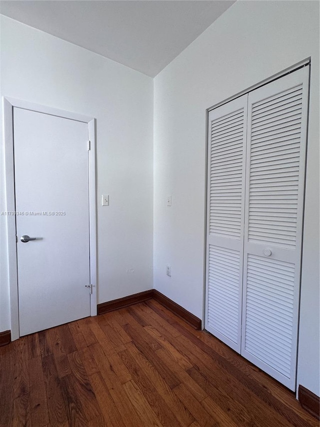 361 Collins Ave Unit A2, Miami Beach, FL 33139 - unfurnished bedroom featuring baseboards, a closet, and wood finished floors