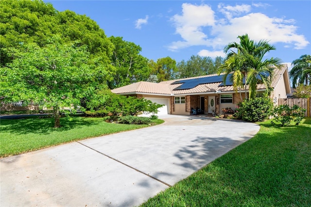 view of front of property featuring an attached garage, roof mounted solar panels, a tiled roof, concrete driveway, and a front yard