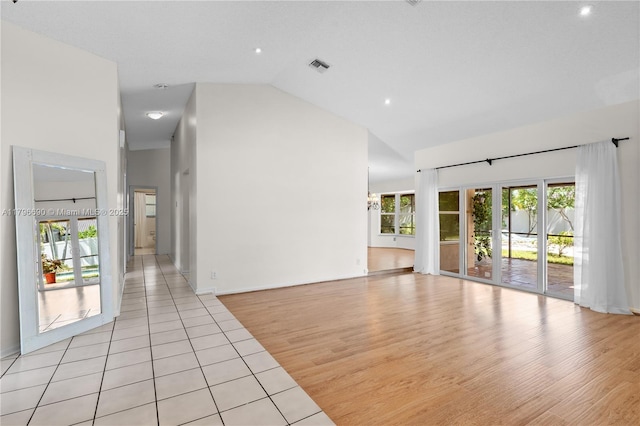 unfurnished living room with light wood finished floors, visible vents, and high vaulted ceiling