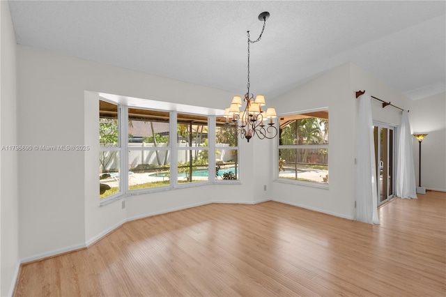 unfurnished dining area featuring baseboards, lofted ceiling, a chandelier, and wood finished floors