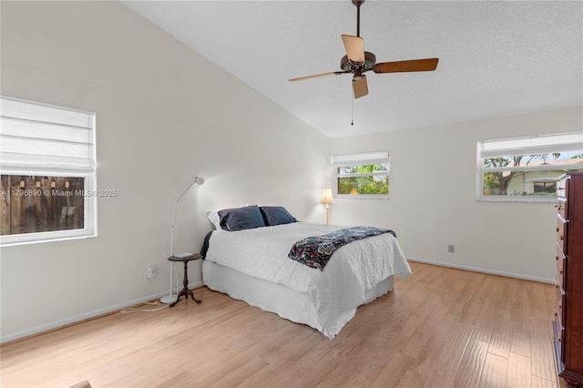 bedroom with light wood finished floors, vaulted ceiling, baseboards, and a ceiling fan