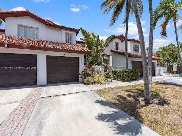 mediterranean / spanish-style house featuring concrete driveway, an attached garage, stucco siding, and a tiled roof