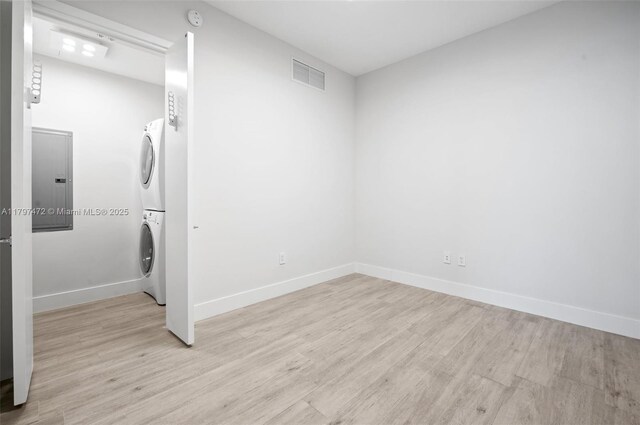 10201 Collins Ave Unit 303, Bal Harbour, FL 33154 - laundry room featuring stacked washer / drying machine, light wood-type flooring, and baseboards