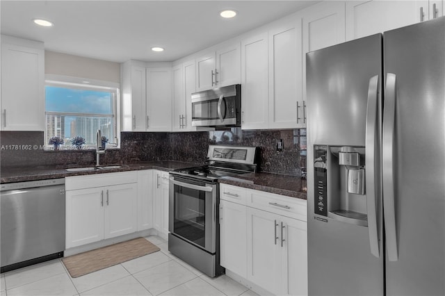 kitchen featuring white cabinetry, stainless steel appliances, decorative backsplash, and a sink