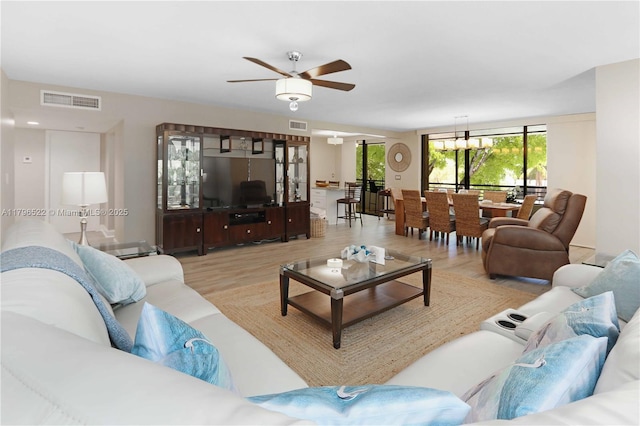 living room with light wood-type flooring, visible vents, and a ceiling fan