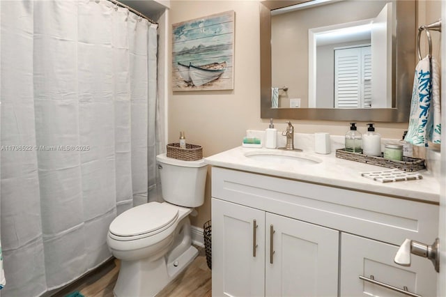 bathroom with toilet, a shower with shower curtain, wood finished floors, and vanity
