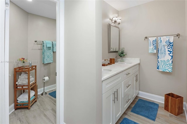 bathroom featuring baseboards, double vanity, and a sink