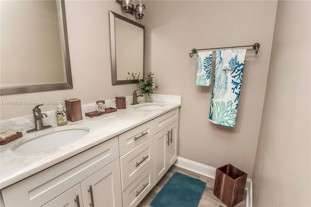 bathroom with a sink, double vanity, baseboards, and wood finished floors