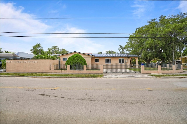 single story home featuring a fenced front yard, stucco siding, metal roof, and a standing seam roof