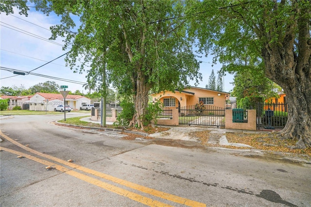 bungalow-style house with a fenced front yard, stucco siding, and a gate