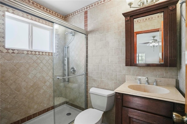 bathroom featuring toilet, vanity, tile walls, and a shower stall