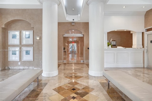 foyer featuring ornate columns, crown molding, arched walkways, marble finish floor, and recessed lighting