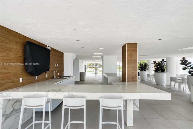 770 Claughton Island Dr Unit 1114, Miami, FL 33131 - kitchen featuring wooden walls, tile patterned floors, light stone countertops, a kitchen breakfast bar, and a textured ceiling