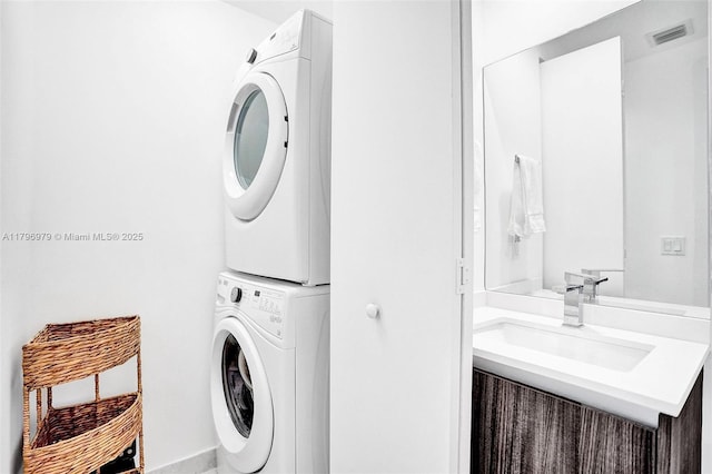 laundry area featuring visible vents, laundry area, stacked washer / dryer, and a sink
