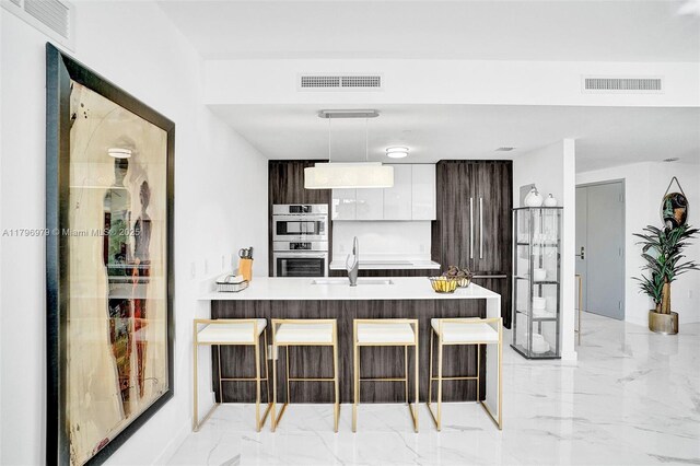 488 NE 18th St Unit 208, Miami, FL 33132 - kitchen with double oven, modern cabinets, a kitchen bar, a peninsula, and light marble finish flooring