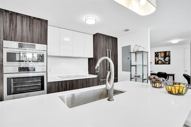488 NE 18th St Unit 208, Miami, FL 33132 - kitchen with double oven, dark brown cabinets, white cabinetry, and light countertops
