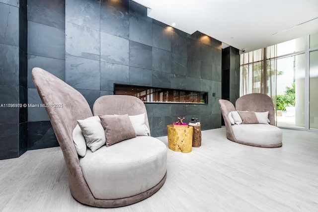 488 NE 18th St Unit 208, Miami, FL 33132 - sitting room with a fireplace, wood finished floors, tile walls, and a wall of windows