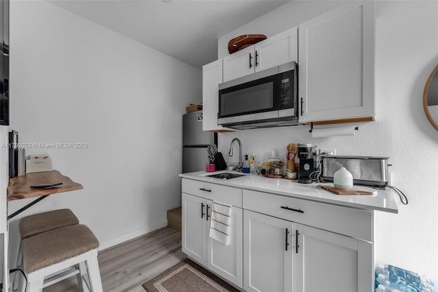 13211 SW 6th St, Miami, FL 33184 - kitchen with light wood finished floors, a sink, stainless steel appliances, white cabinetry, and light countertops