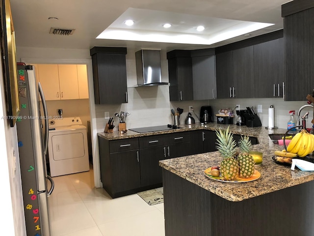 kitchen with freestanding refrigerator, a tray ceiling, visible vents, wall chimney range hood, and black electric stovetop