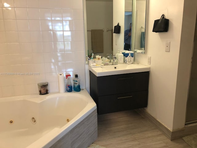 bathroom featuring baseboards, a tub with jets, and vanity