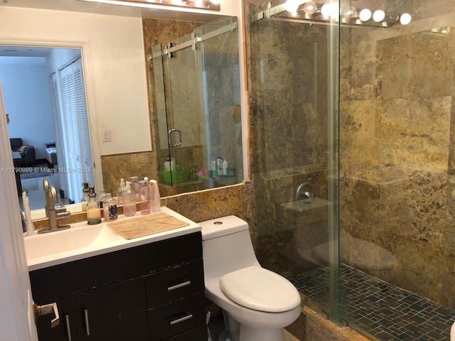 bathroom with a stall shower, tile walls, vanity, and toilet