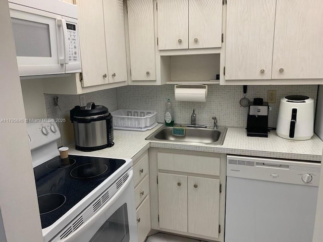kitchen with backsplash, light countertops, a sink, and white appliances