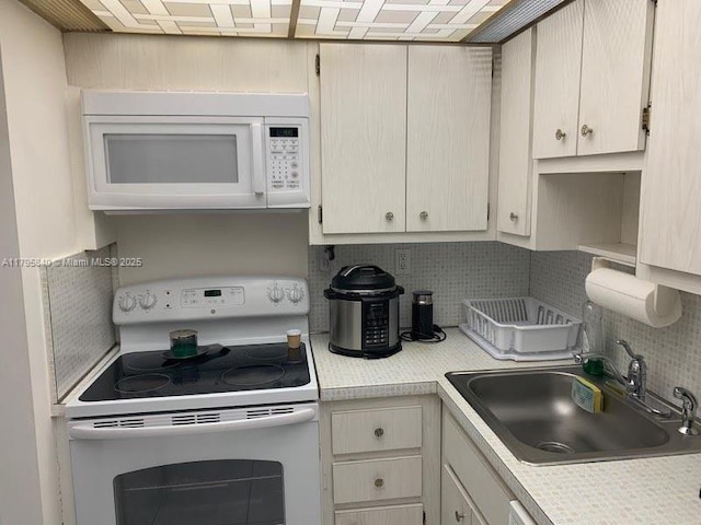 kitchen with white appliances, decorative backsplash, light countertops, and a sink
