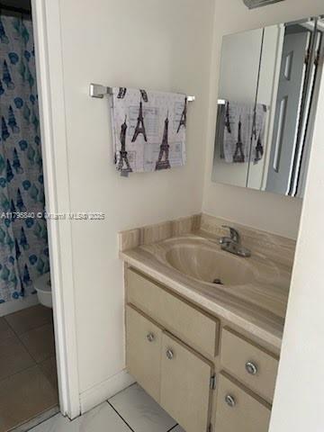 full bath featuring toilet, vanity, curtained shower, tile patterned flooring, and baseboards