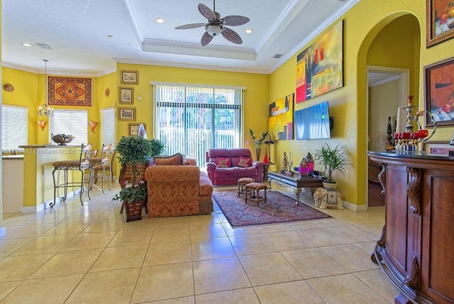 living area featuring light tile patterned floors, crown molding, visible vents, ceiling fan, and arched walkways