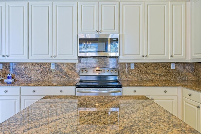 kitchen featuring dark stone countertops, white cabinets, appliances with stainless steel finishes, and decorative backsplash
