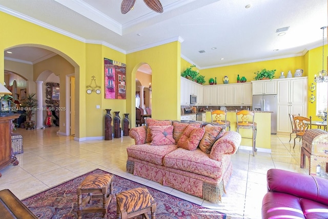 living room with crown molding, arched walkways, a ceiling fan, light tile patterned floors, and baseboards