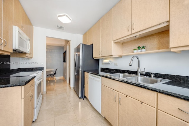 kitchen featuring visible vents, light brown cabinetry, a sink, and white appliances