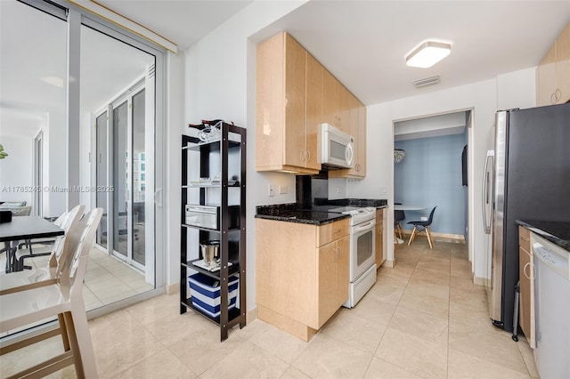 kitchen featuring white appliances, light brown cabinets, dark stone counters, and visible vents