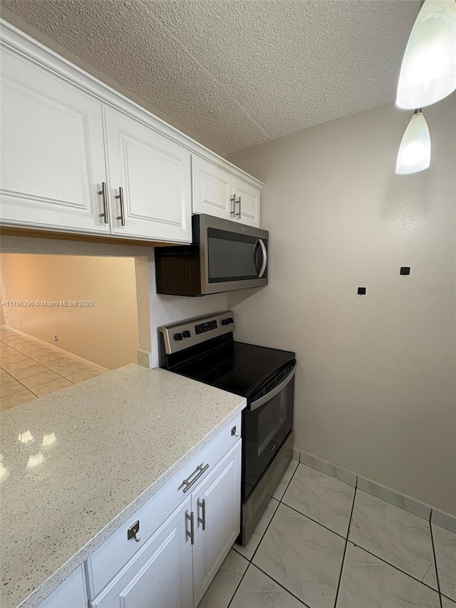 kitchen with marble finish floor, a textured ceiling, white cabinets, baseboards, and appliances with stainless steel finishes
