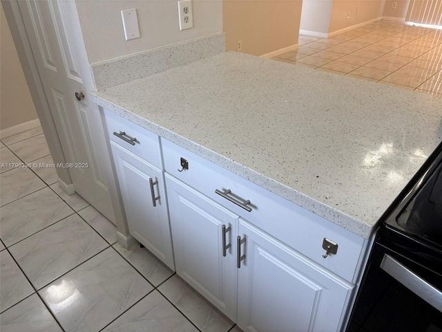 details with black electric range oven, light stone countertops, baseboards, and white cabinets