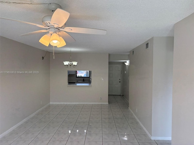 spare room featuring a textured ceiling, light tile patterned flooring, ceiling fan with notable chandelier, and visible vents