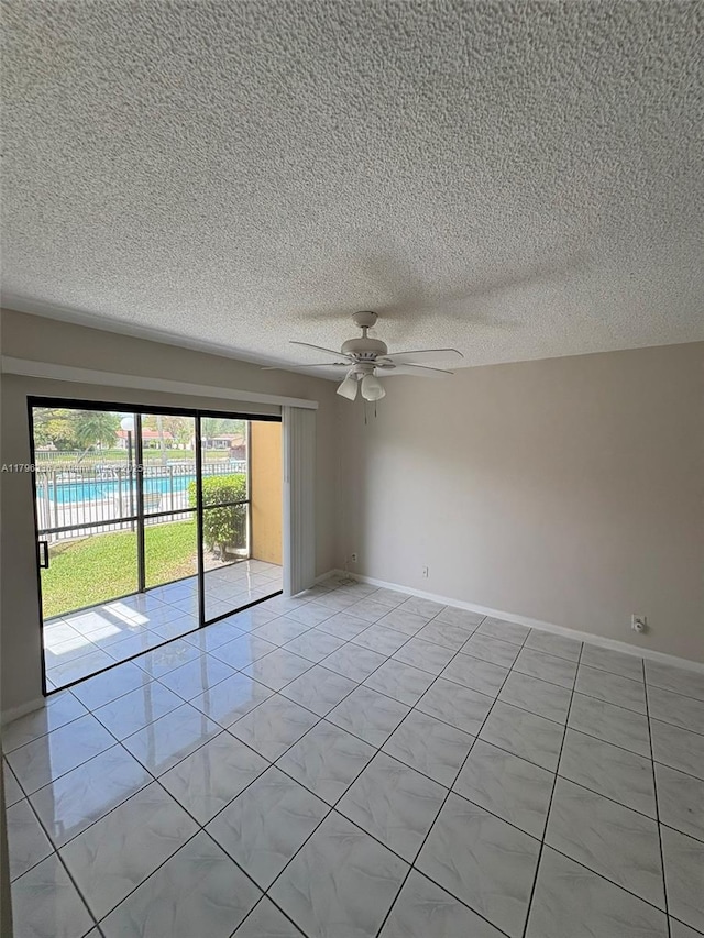 empty room featuring a textured ceiling, baseboards, light tile patterned floors, and ceiling fan