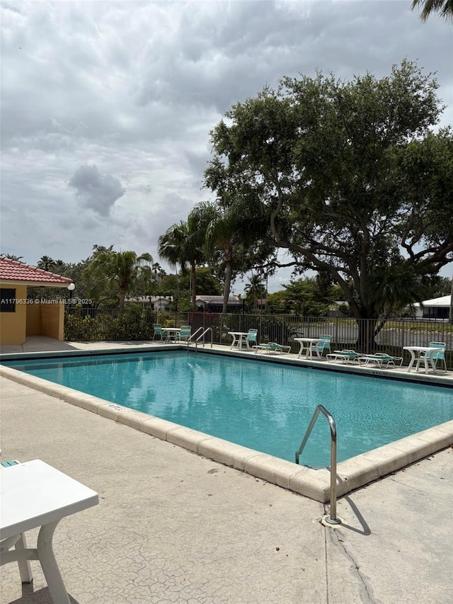 community pool with a patio and fence